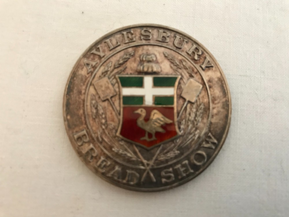 A circular 1935 silver prize medal with a central enamel shield detailing, resting inside an open red velvet-lined presentation box. View III