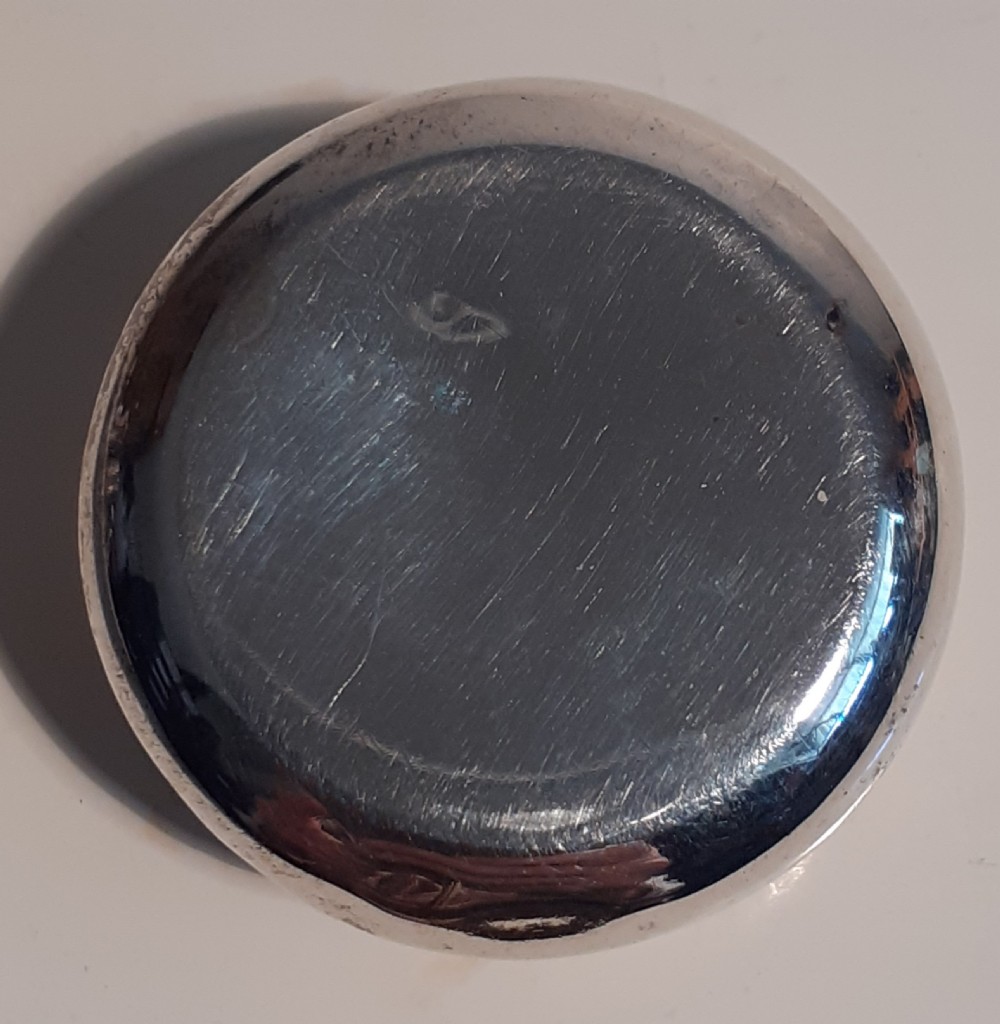 A circular antique sterling silver pill box featuring raised scrollwork foliage and an unengraved central cartouche. View IV