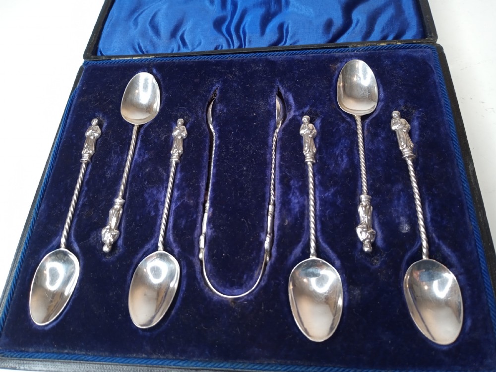 A late Victorian cased sterling silver set featuring six twisted-stem spoons with figural finials and matching sugar tongs housed in a blue velvet-lined box. View II