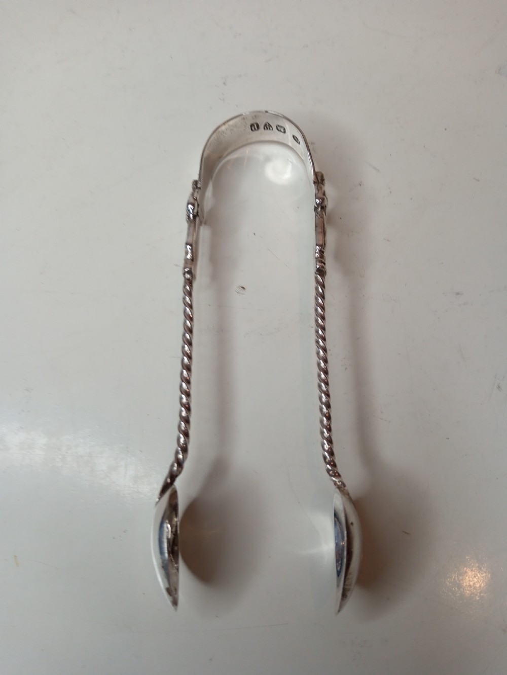 A late Victorian cased sterling silver set featuring six twisted-stem spoons with figural finials and matching sugar tongs housed in a blue velvet-lined box. View VI