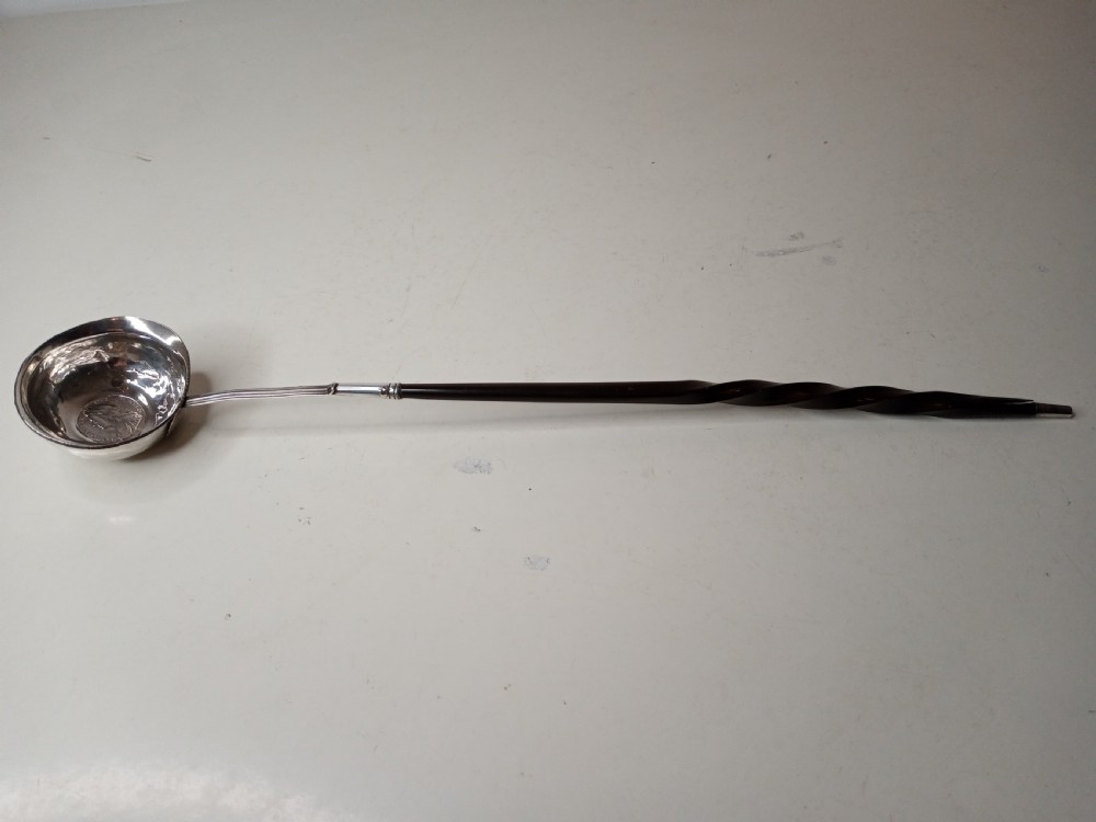 A Georgian silver toddy ladle bowl with an inset George III silver coin at the centre and a reeded handle joint. View II
