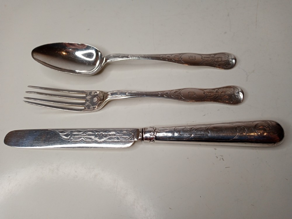 An antique three-piece silver christening cutlery set housed within a open red velvet-lined presentation case. View IV