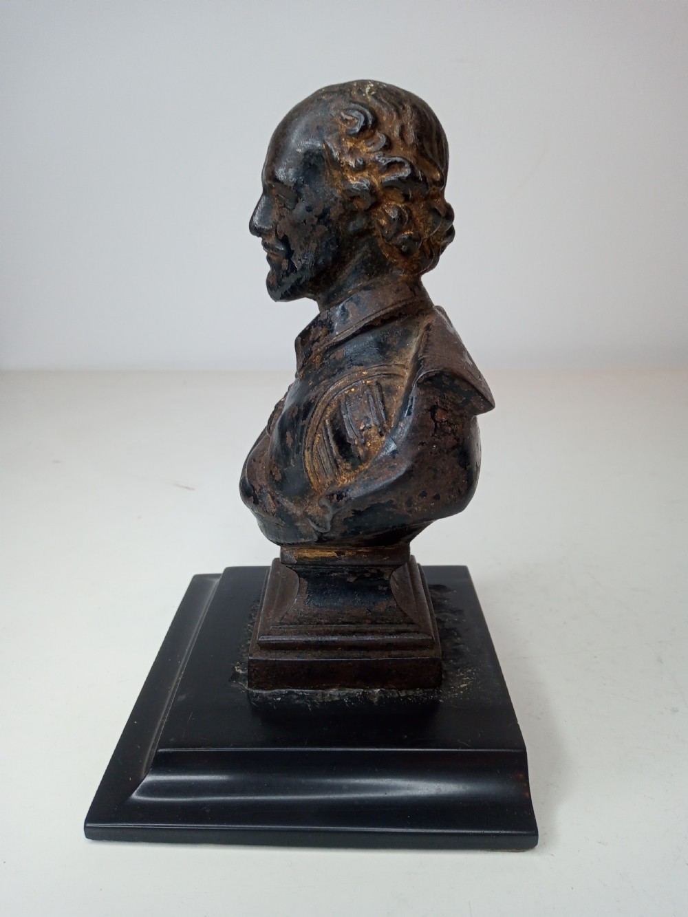 A dark metal portrait bust of William Shakespeare mounted on a square black marble plinth. View III