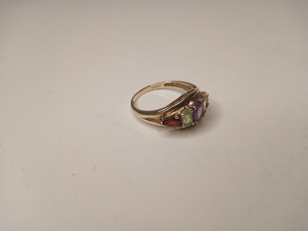 A nine-carat yellow gold ring featuring a horizontal row of five oval gemstones in varied colours within a boat-shaped mount. View IV