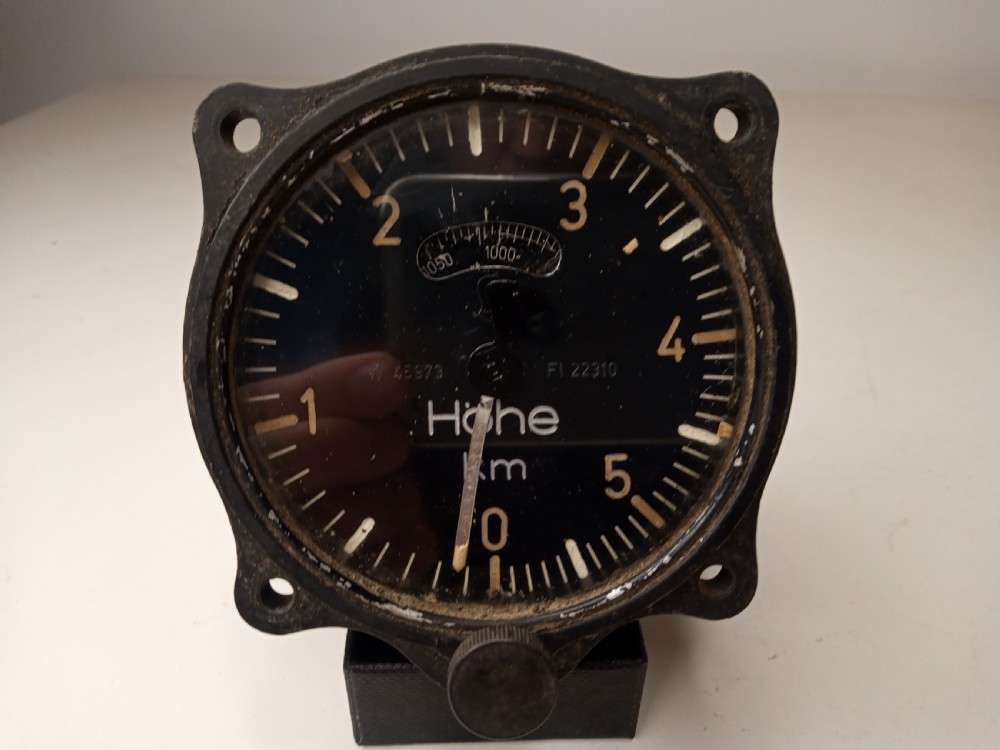 A square black metal Second World War German Luftwaffe aircraft altimeter gauge featuring white dial numbers from zero to five and a central adjustment knob.