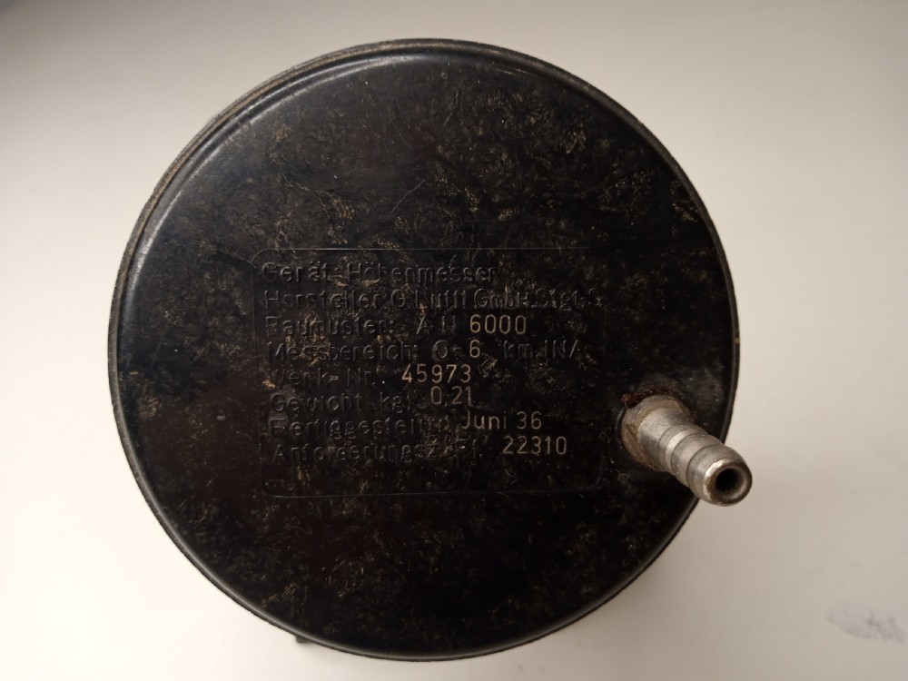 A square black metal Second World War German Luftwaffe aircraft altimeter gauge featuring white dial numbers from zero to five and a central adjustment knob. View IV