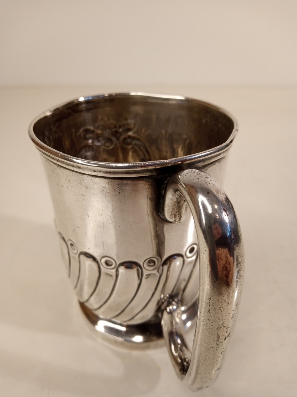 A sterling silver tankard with chased floral decoration and scroll cartouche detailing on a polished surface. View III