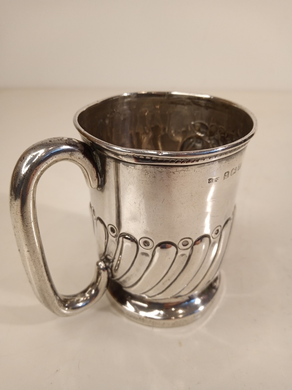 A sterling silver tankard with chased floral decoration and scroll cartouche detailing on a polished surface. View IV