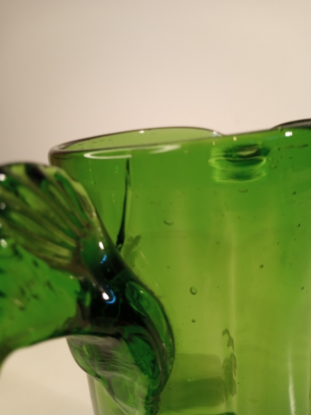A Victorian emerald green glass pitcher featuring white enamel painting of a child figure among foliage, complete with a textured applied handle. View VII