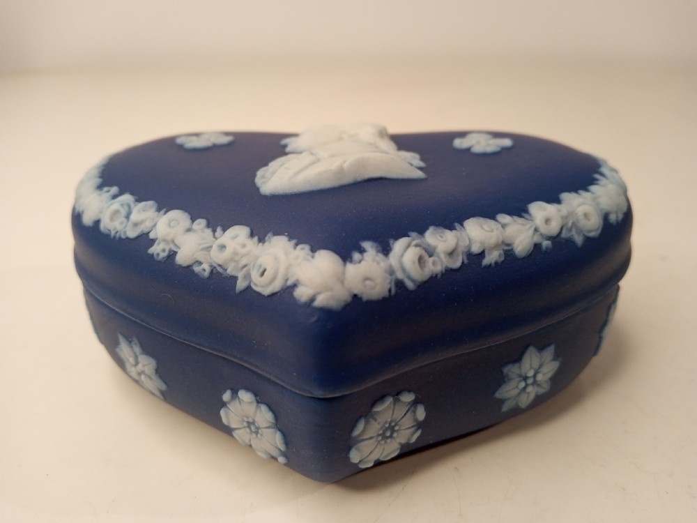 A heart-shaped dark blue Jasperware trinket box lid featuring a white bas-relief profile portrait bust surrounded by floral border accents. View VI