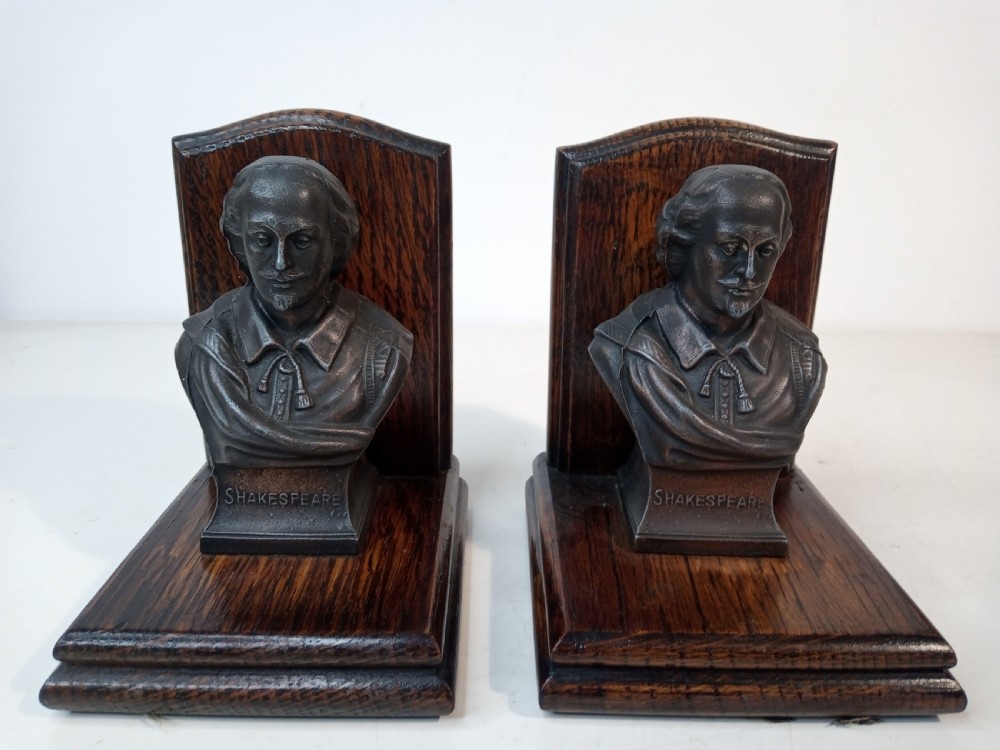 A pair of Art Deco bookends featuring metal busts of William Shakespeare mounted on dark oak bases.