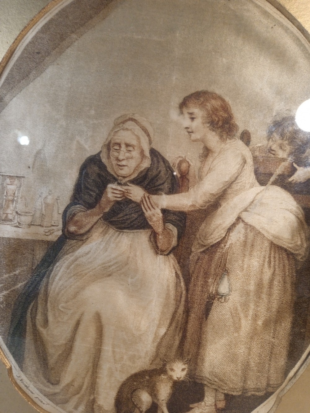 A late Georgian framed stipple engraving printed on silk depicting a domestic scene within an oval vignette, set inside a gilded wooden frame. View III