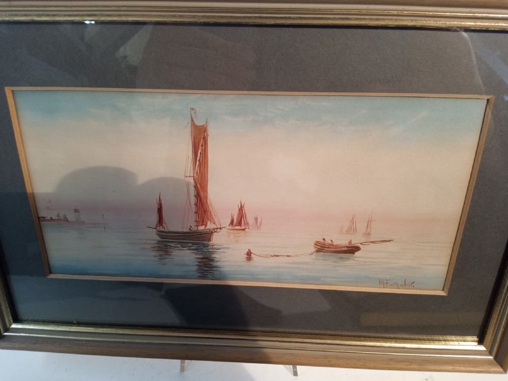 A horizontal nineteenth-century Victorian watercolour painting depicting reddish-brown sailing vessels on calm blue water with a distant lighthouse, housed in a double mount and wooden frame. View III