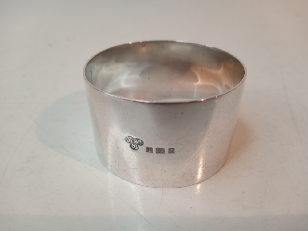 A plain circular sterling silver napkin ring displaying stamped official hallmarks on the polished outer surface.