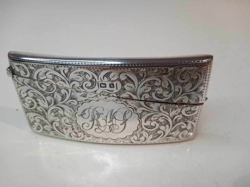 An Edwardian sterling silver card case featuring detailed foliage engraving across a gently curved rectangular body with a hinged cap. View II