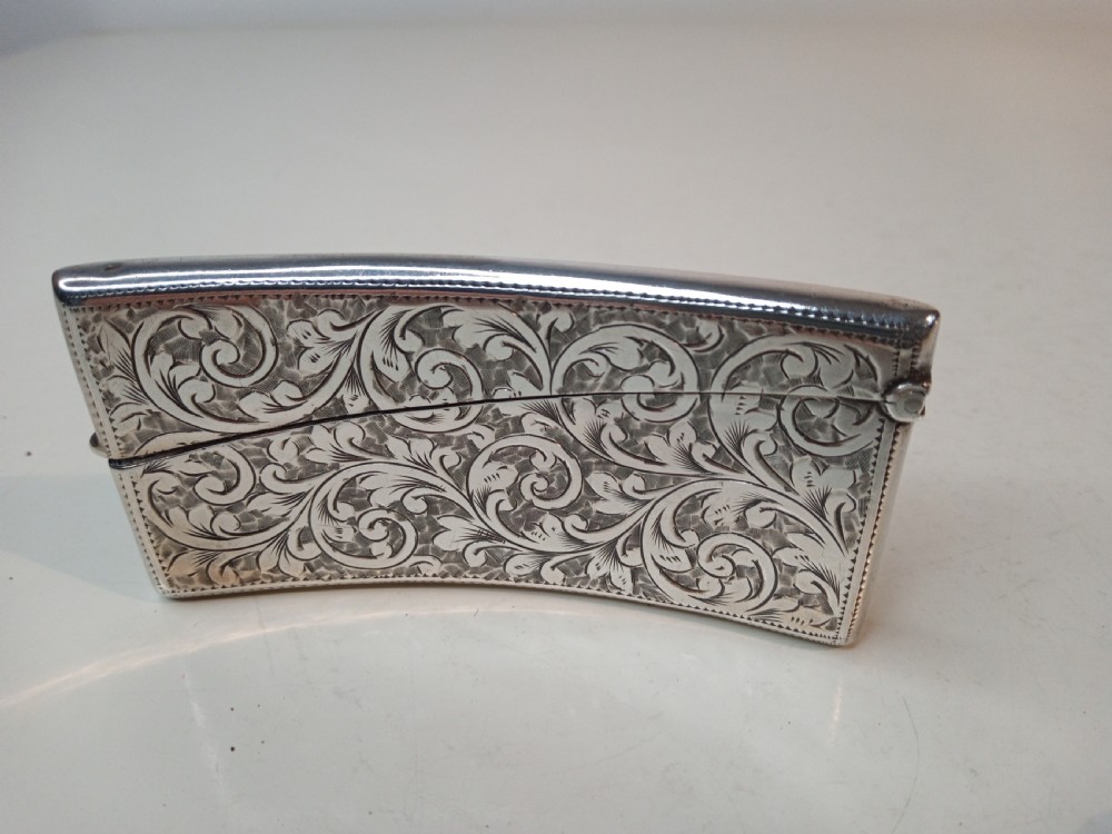 An Edwardian sterling silver card case featuring detailed foliage engraving across a gently curved rectangular body with a hinged cap. View III
