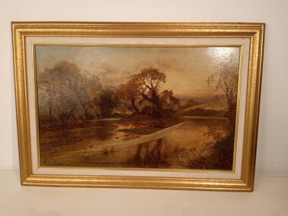 An antique oil painting depicting a river scene surrounded by trees, housed within a moulded gilt frame. View IV