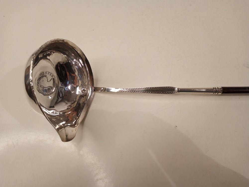 A mid-eighteenth century sterling silver punch ladle featuring a deep circular silver bowl and a long twisted dark handle. View III