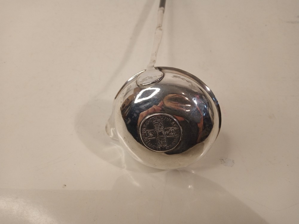 A mid-eighteenth century sterling silver punch ladle featuring a deep circular silver bowl and a long twisted dark handle. View V
