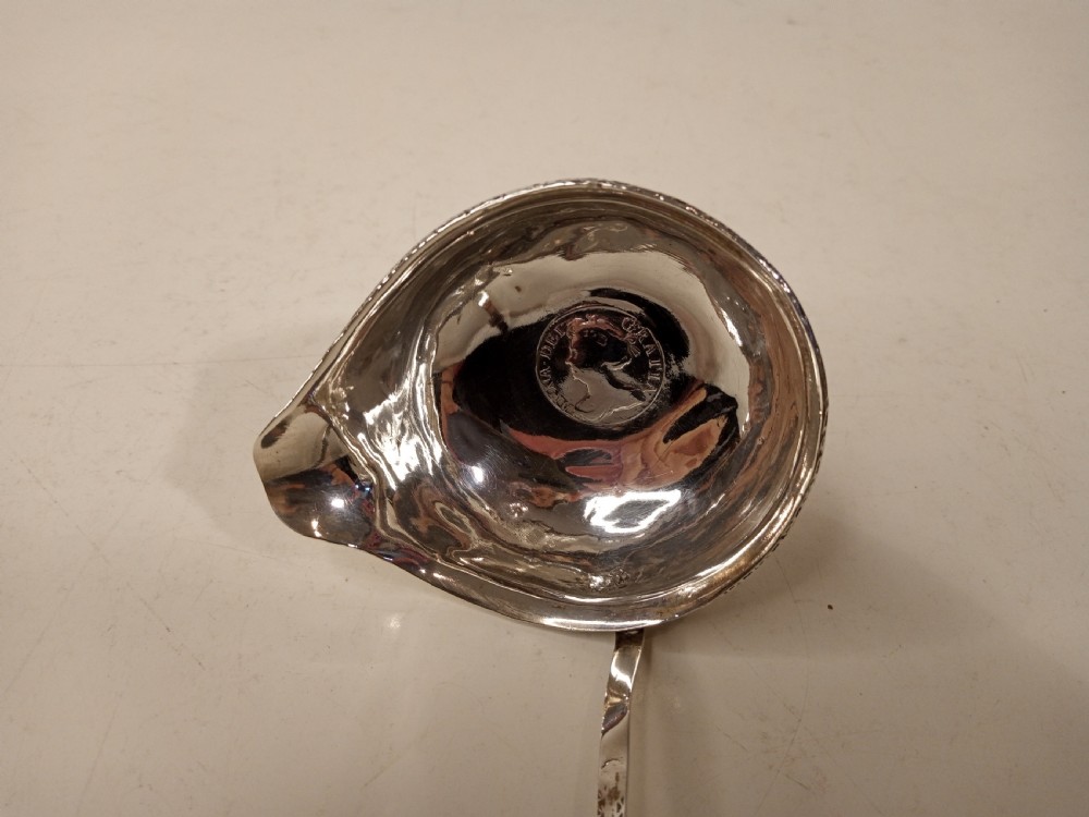A mid-eighteenth century sterling silver punch ladle featuring a deep circular silver bowl and a long twisted dark handle. View VII