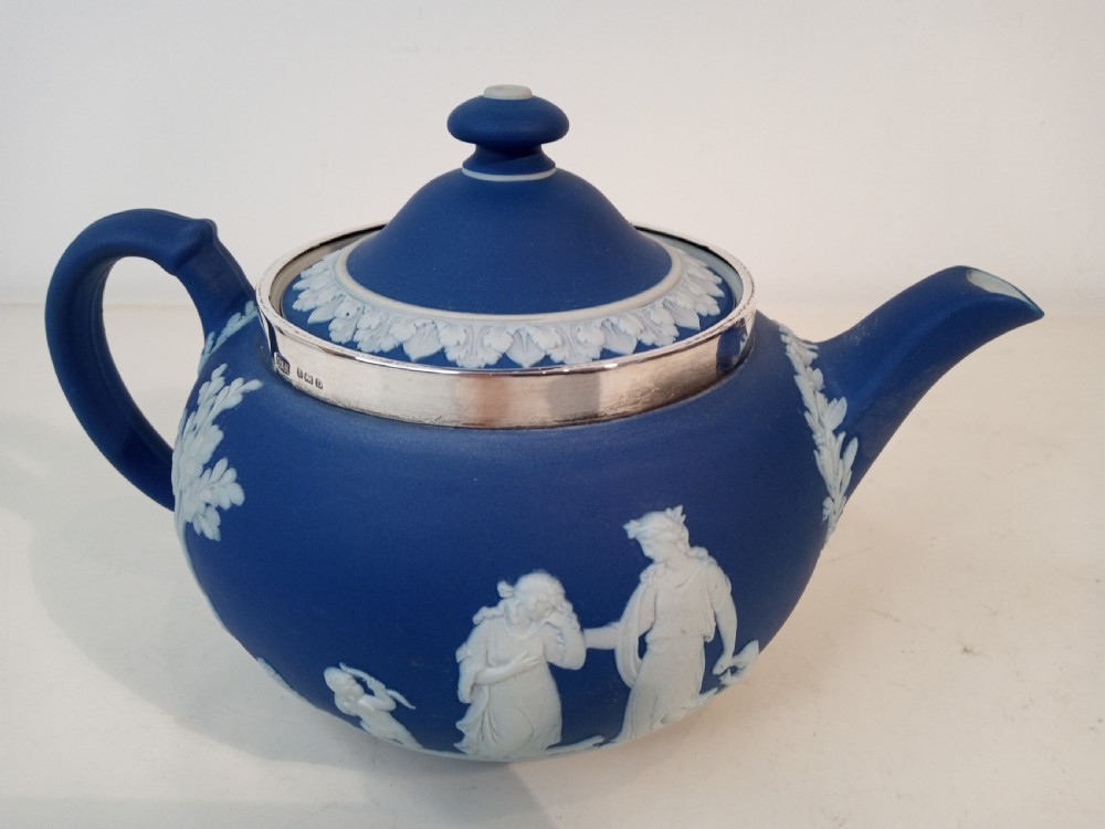 A blue stoneware teapot featuring white neoclassical bas-relief figures and a silver collar around the rim. View II