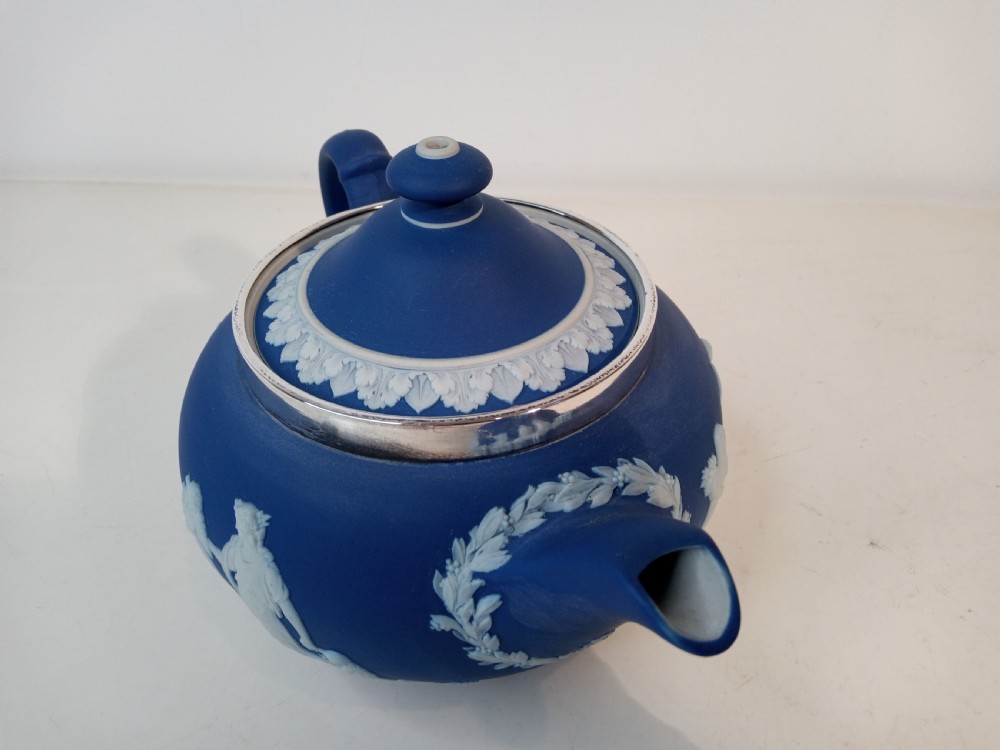 A blue stoneware teapot featuring white neoclassical bas-relief figures and a silver collar around the rim. View III