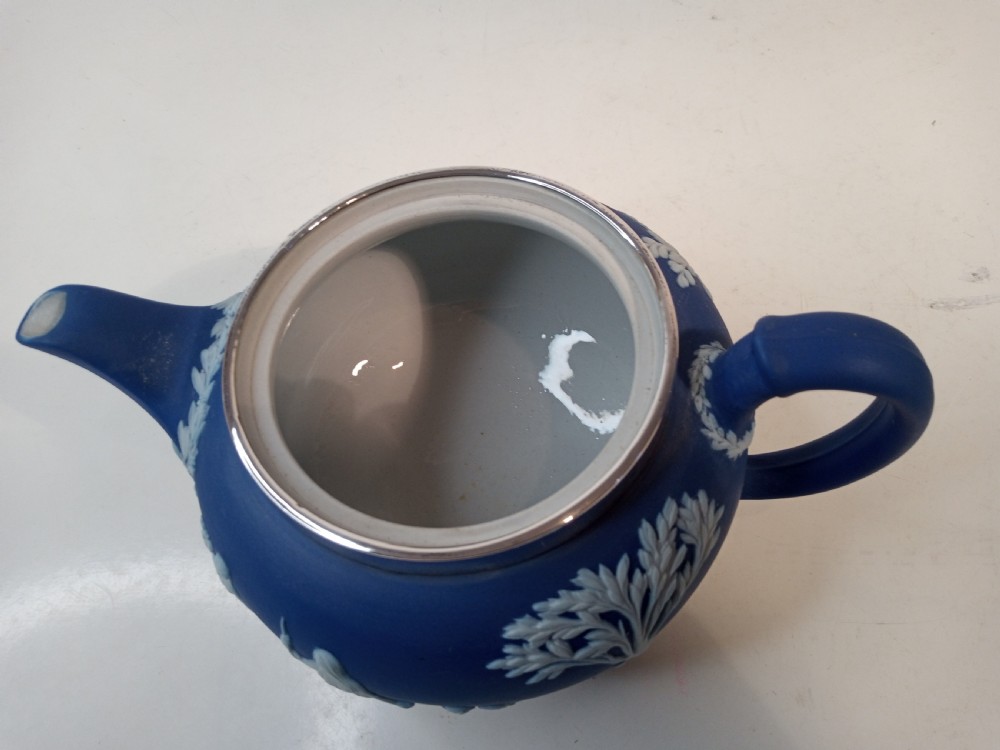 A blue stoneware teapot featuring white neoclassical bas-relief figures and a silver collar around the rim. View VII