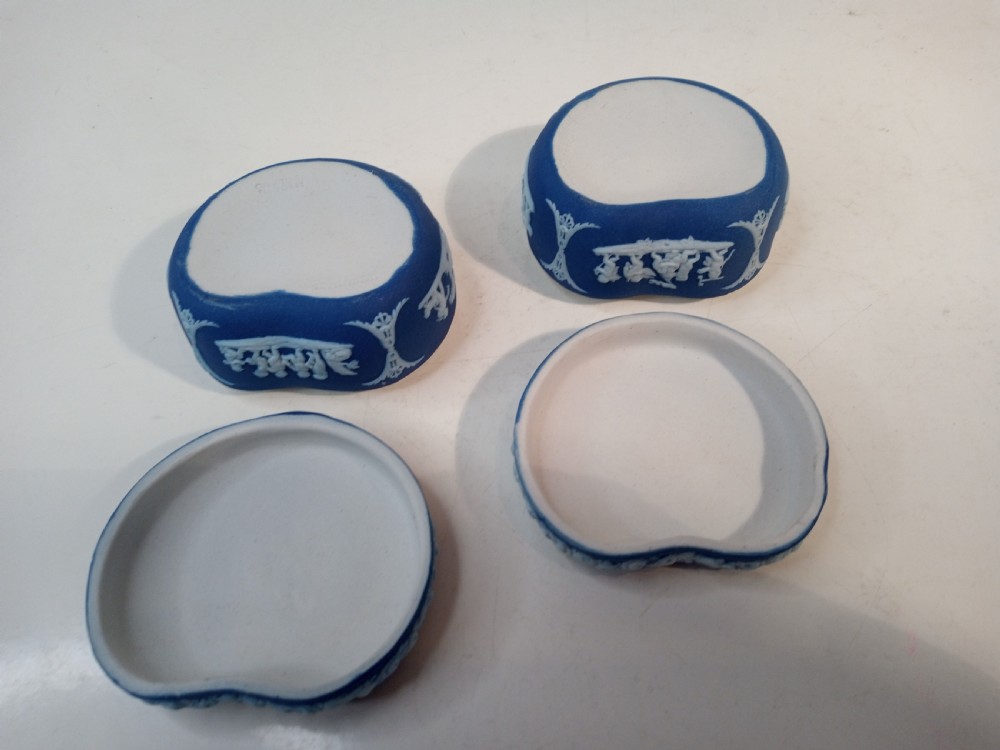 A pair of kidney-shaped blue Wedgwood jasperware trinket boxes with white classical bas-relief scenes on their lids. View II