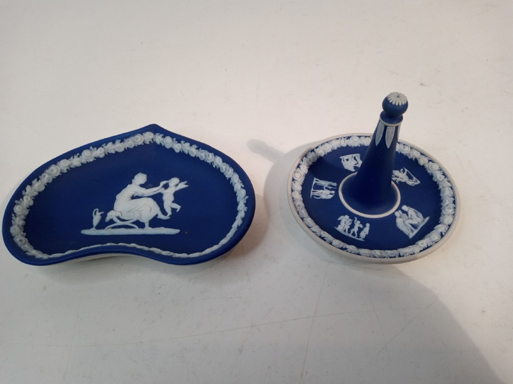 A dark blue Wedgwood jasperware heart-shaped tray alongside a matching circular ring stand featuring white classical bas-relief motifs.