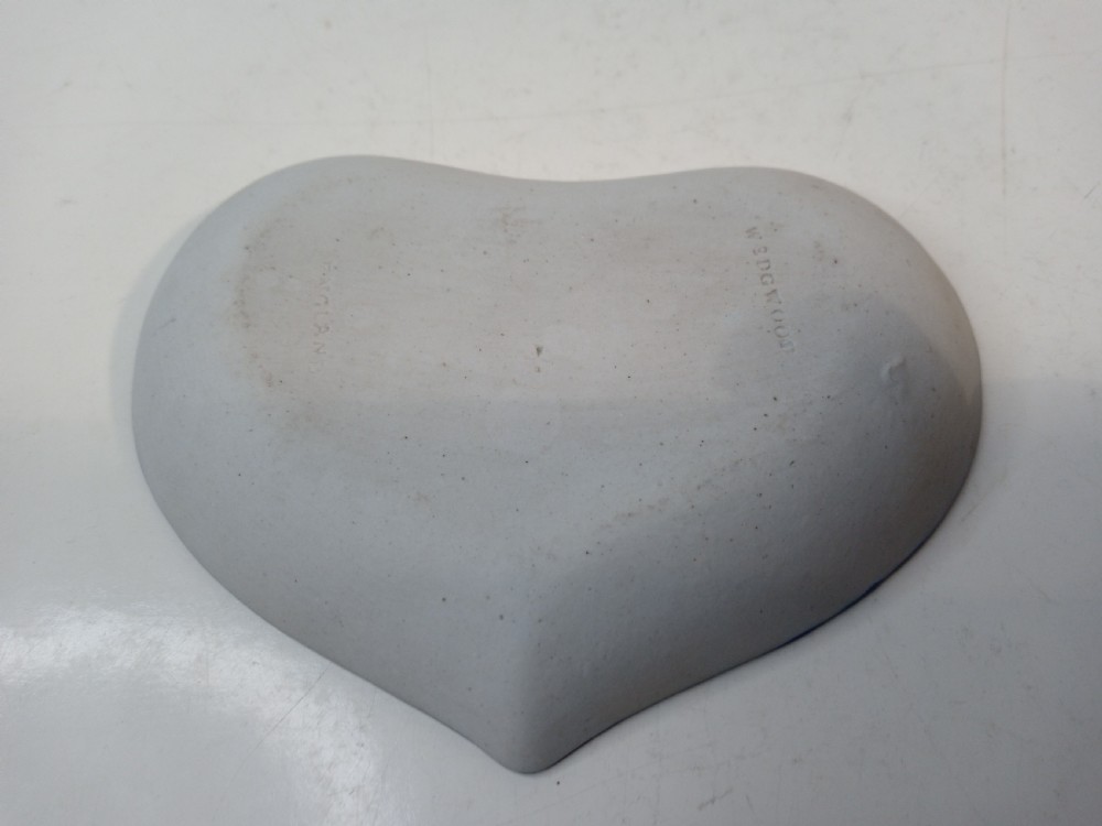 A dark blue Wedgwood jasperware heart-shaped tray alongside a matching circular ring stand featuring white classical bas-relief motifs. View V