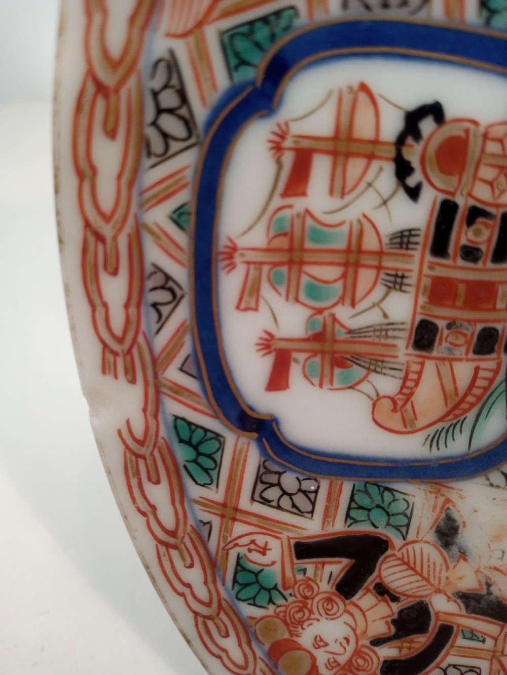 A four-piece Japanese Imari porcelain set featuring three patterned display plates and a matching small bowl decorated with European ship motifs in red, blue, and gold. View IV