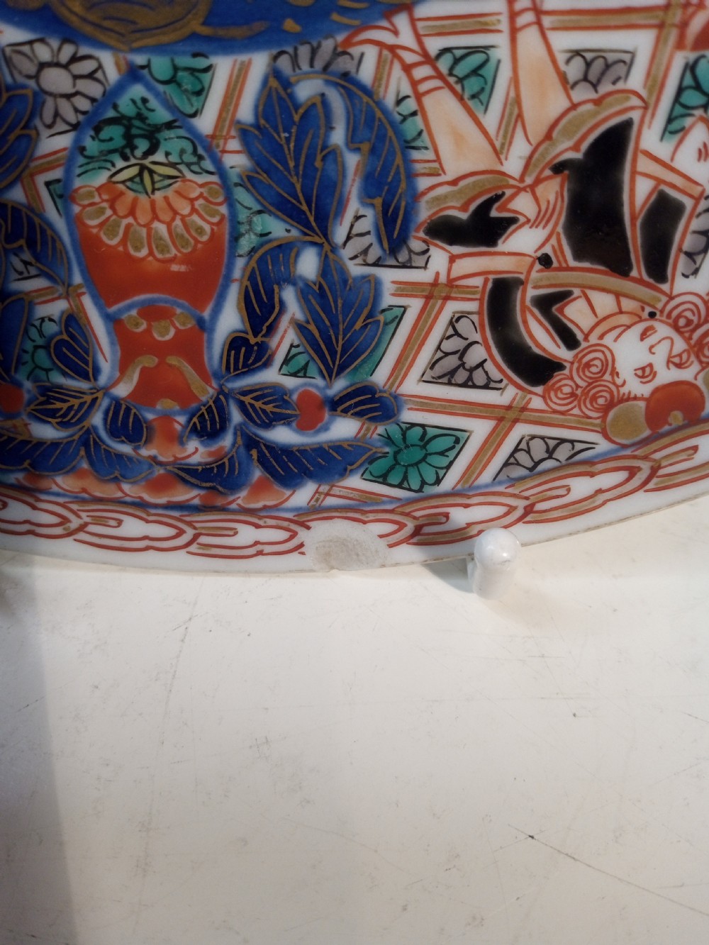 A four-piece Japanese Imari porcelain set featuring three patterned display plates and a matching small bowl decorated with European ship motifs in red, blue, and gold. View VI