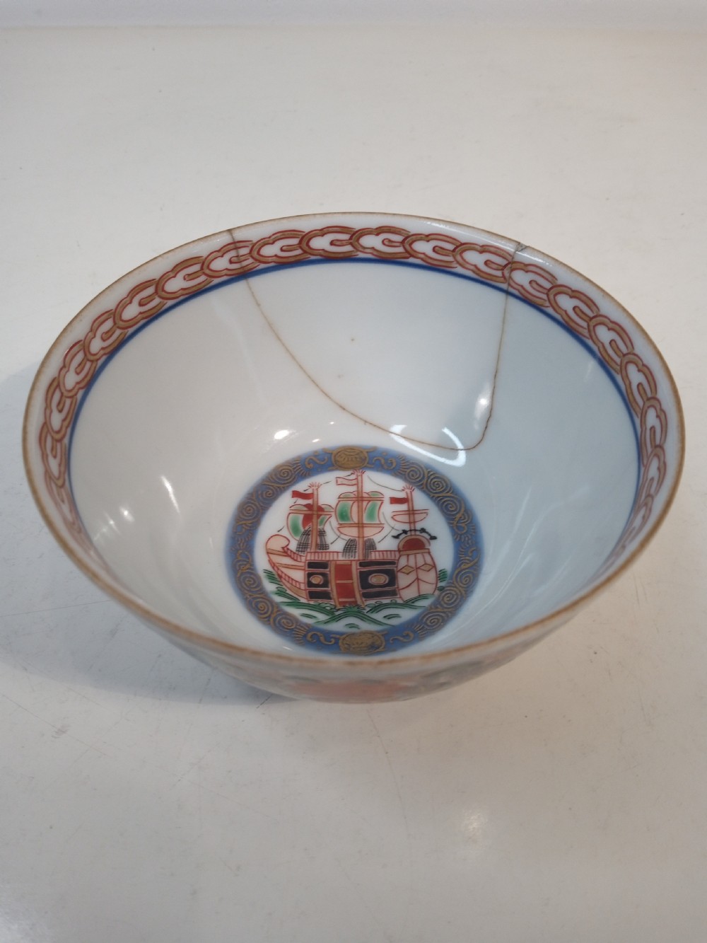 A four-piece Japanese Imari porcelain set featuring three patterned display plates and a matching small bowl decorated with European ship motifs in red, blue, and gold. View IX