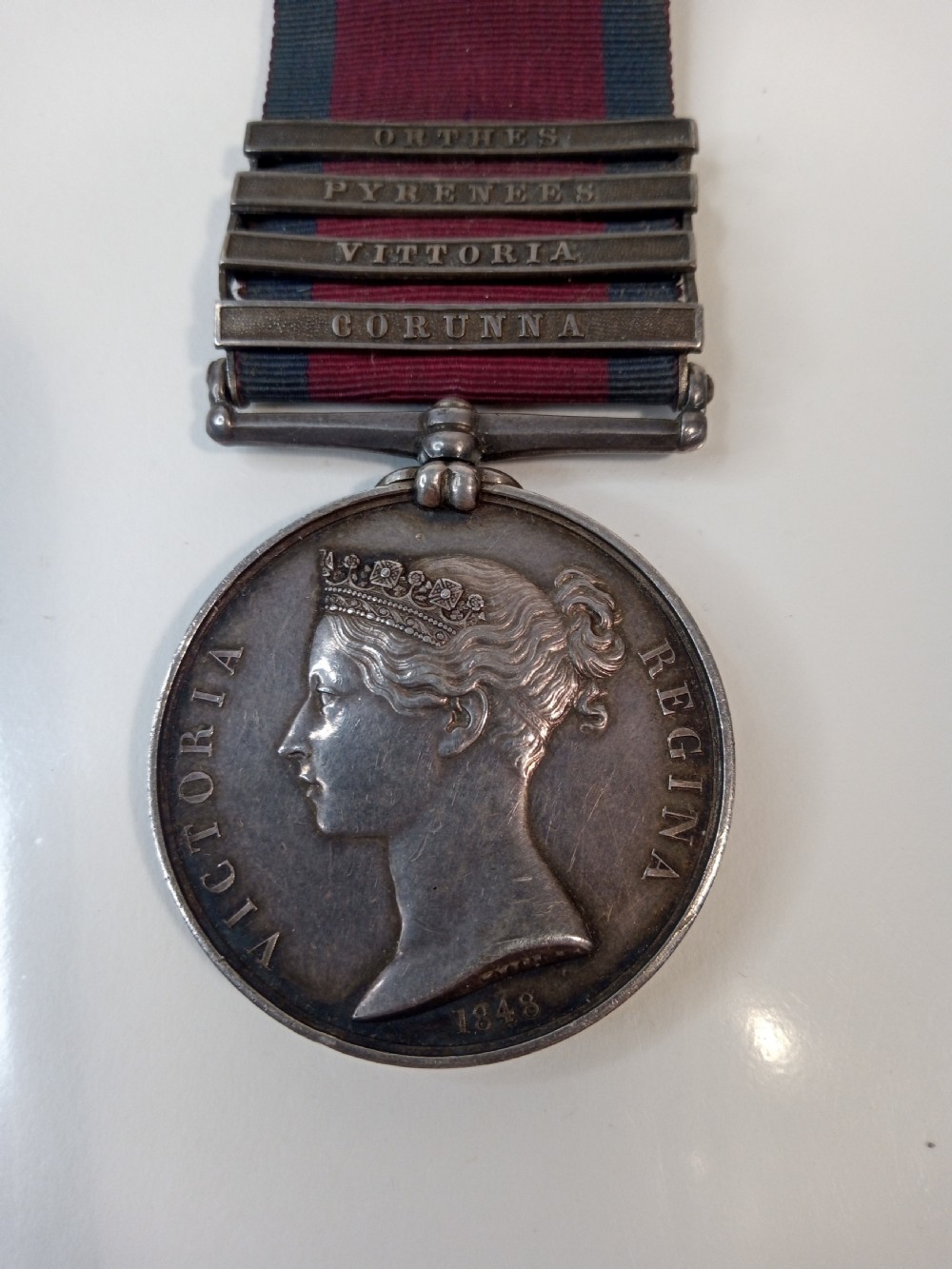A Victorian silver Military General Service Medal dated 1848 featuring four campaign clasps and Queen Victoria profile on a crimson and blue ribbon.