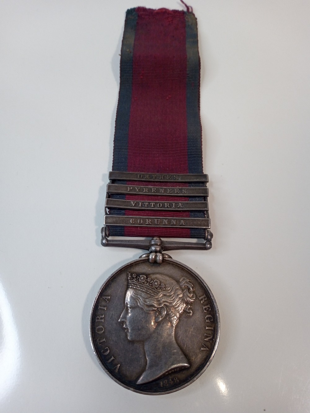 A Victorian silver Military General Service Medal dated 1848 featuring four campaign clasps and Queen Victoria profile on a crimson and blue ribbon. View II