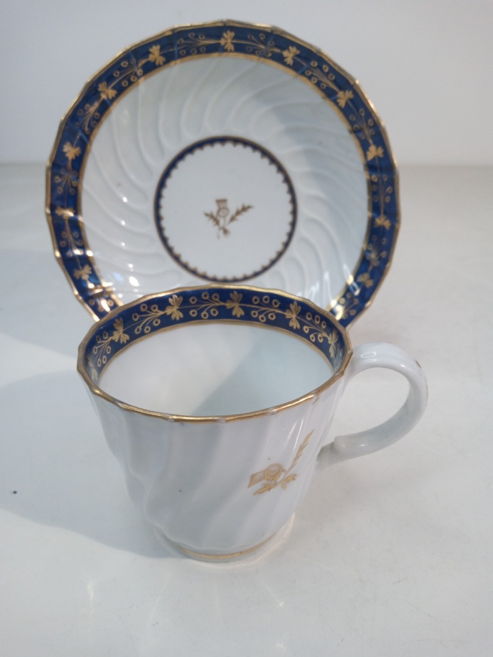 A Georgian Worcester spiral-fluted porcelain teacup and saucer with cobalt blue and gilt foliate borders.