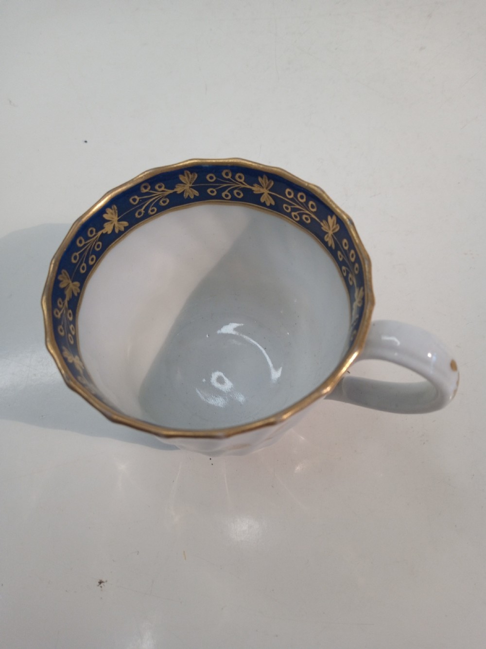 A Georgian Worcester spiral-fluted porcelain teacup and saucer with cobalt blue and gilt foliate borders. View V