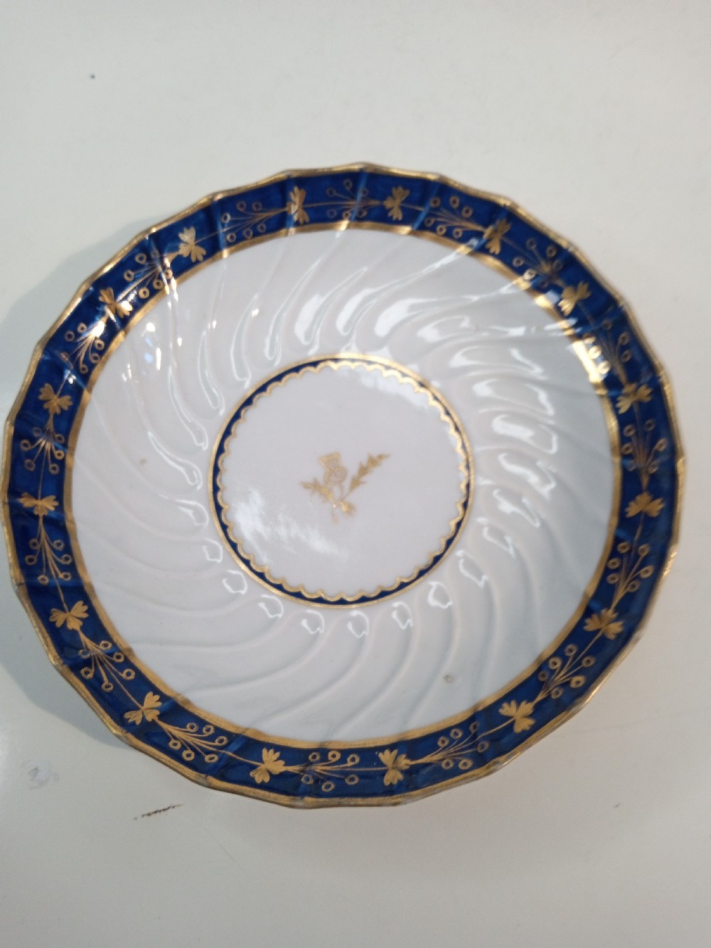A Georgian Worcester spiral-fluted porcelain teacup and saucer with cobalt blue and gilt foliate borders. View VI