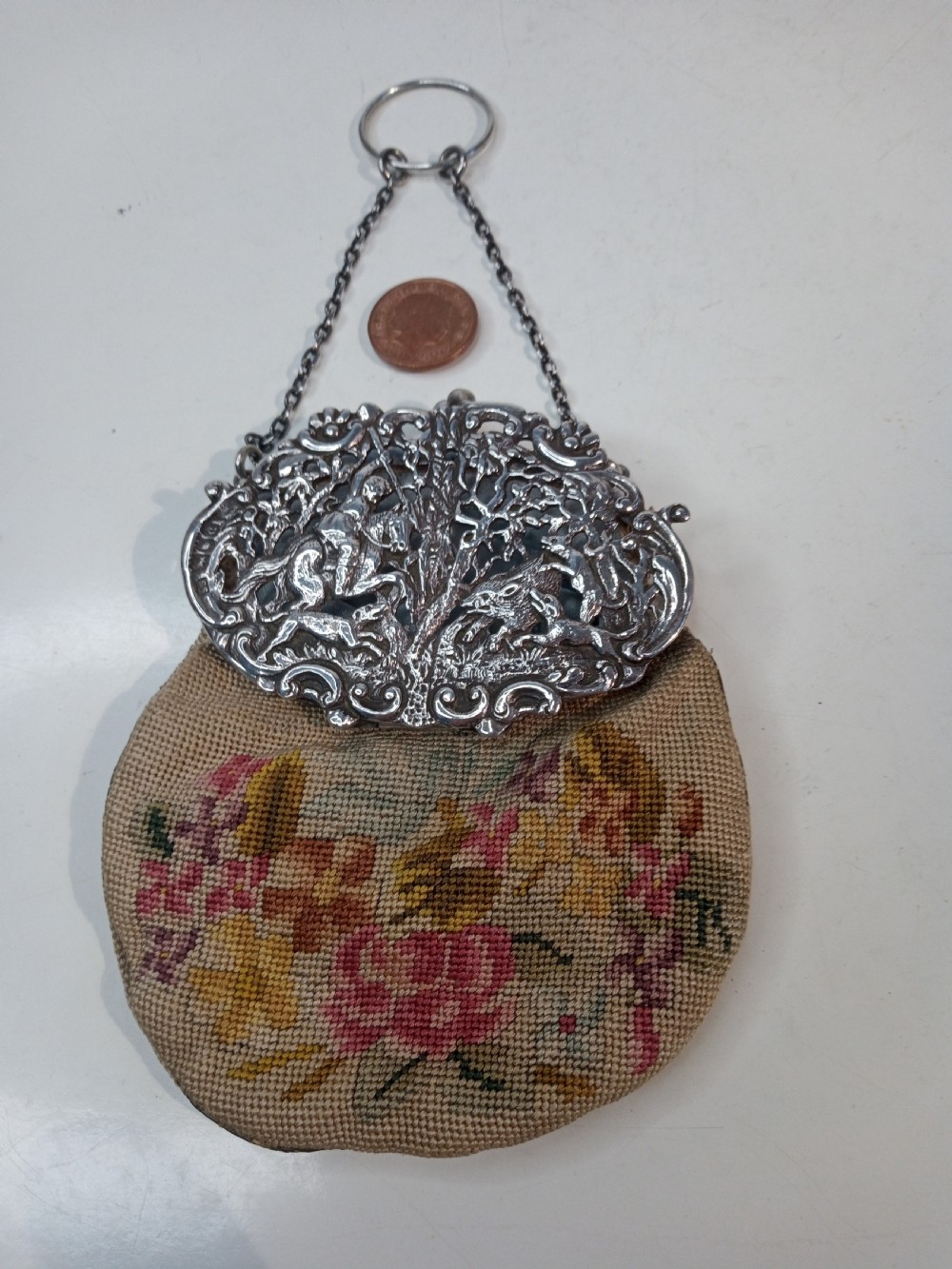 Late Victorian sterling silver evening purse featuring a pierced silver frame with a chain handle and a beige petit point needlepoint pouch with pink and yellow floral embroidery. View VI