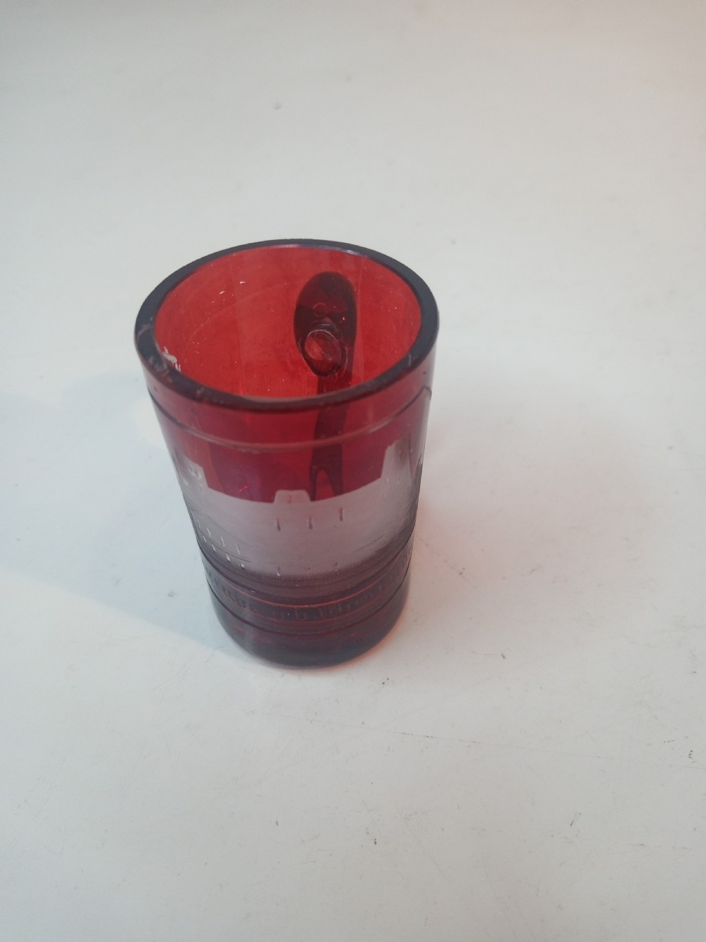A late Victorian miniature ruby glass tankard with an applied red handle and a white etched architectural motif on the body. View III