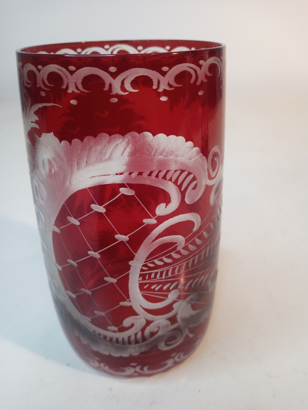 A pair of ruby red glass tumblers featuring white wheel-engraved stag and forest motifs with decorative scrollwork borders. View VII