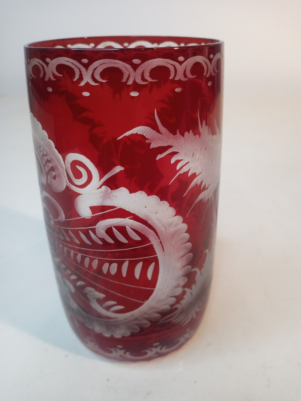 A pair of ruby red glass tumblers featuring white wheel-engraved stag and forest motifs with decorative scrollwork borders. View VIII
