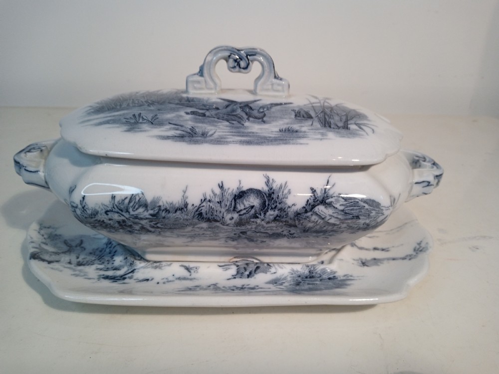 A Victorian Staffordshire earthenware tureen and matching stand with blue and white transferware illustrations of waterfowl and rabbits.