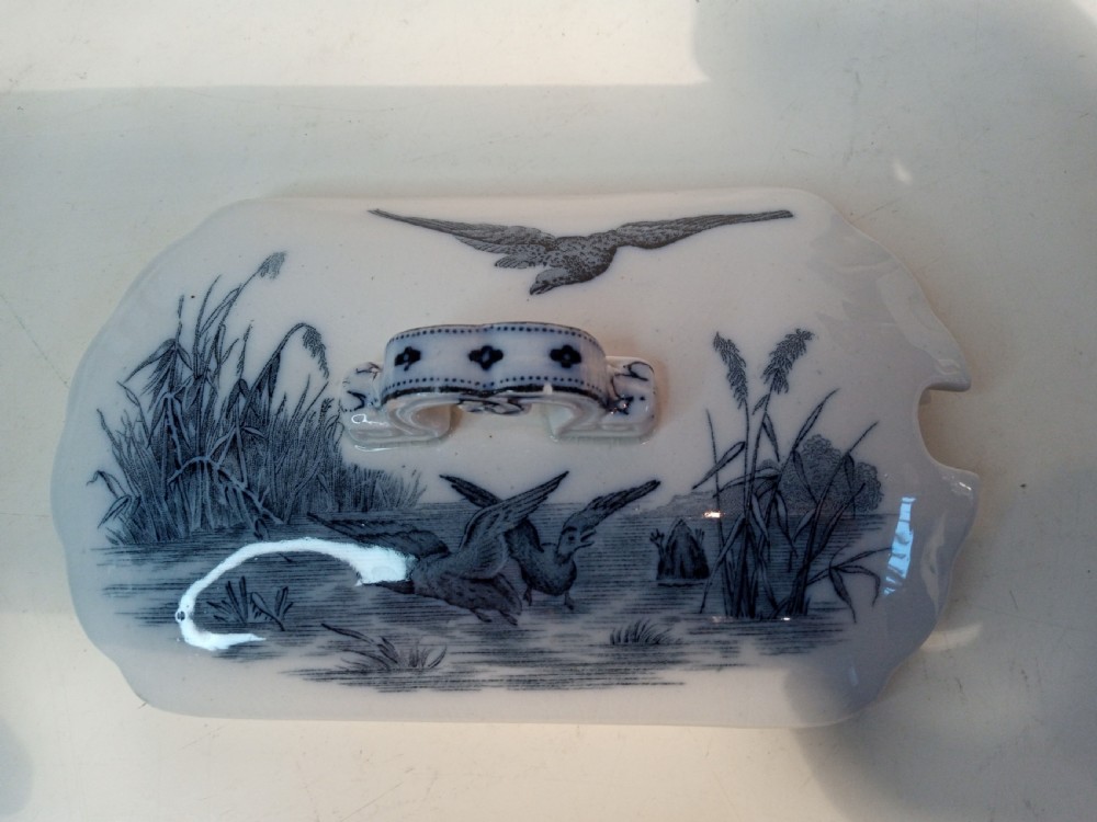 A Victorian Staffordshire earthenware tureen and matching stand with blue and white transferware illustrations of waterfowl and rabbits. View VII