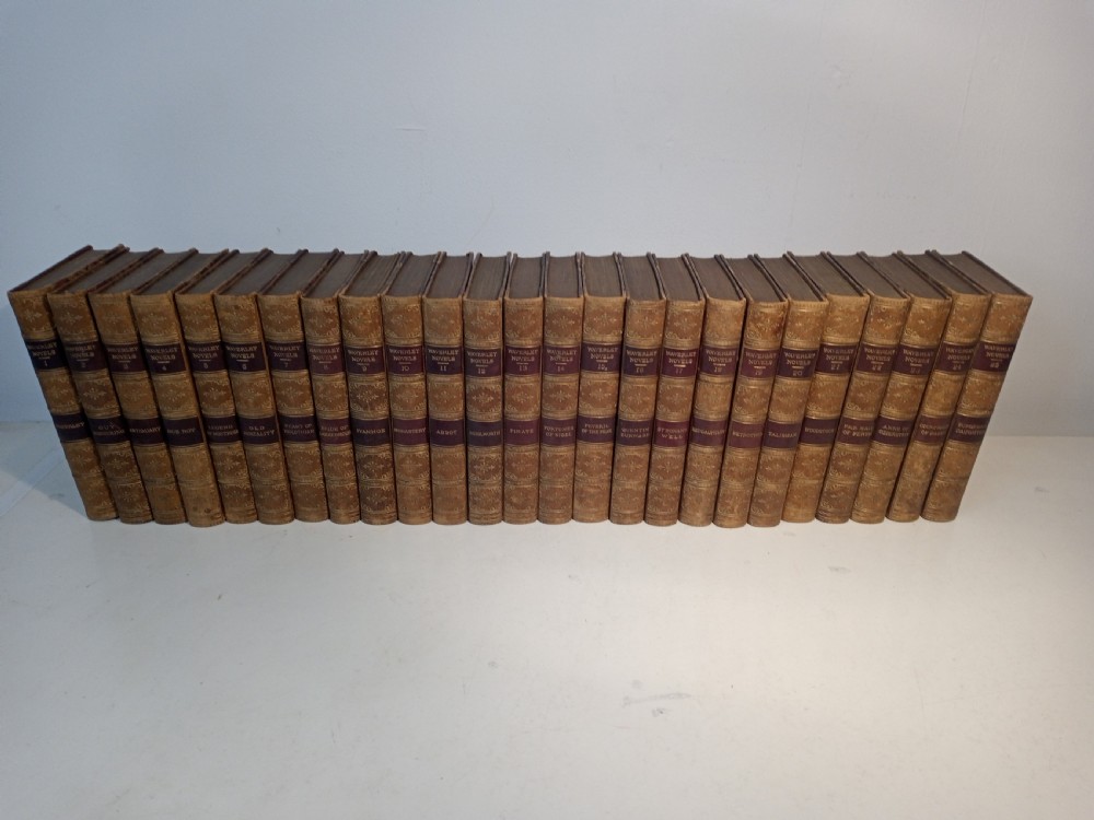 A complete set of 25 Victorian leather-bound Waverley Novels arranged side by side with gilt tooling and red title blocks along the spines.