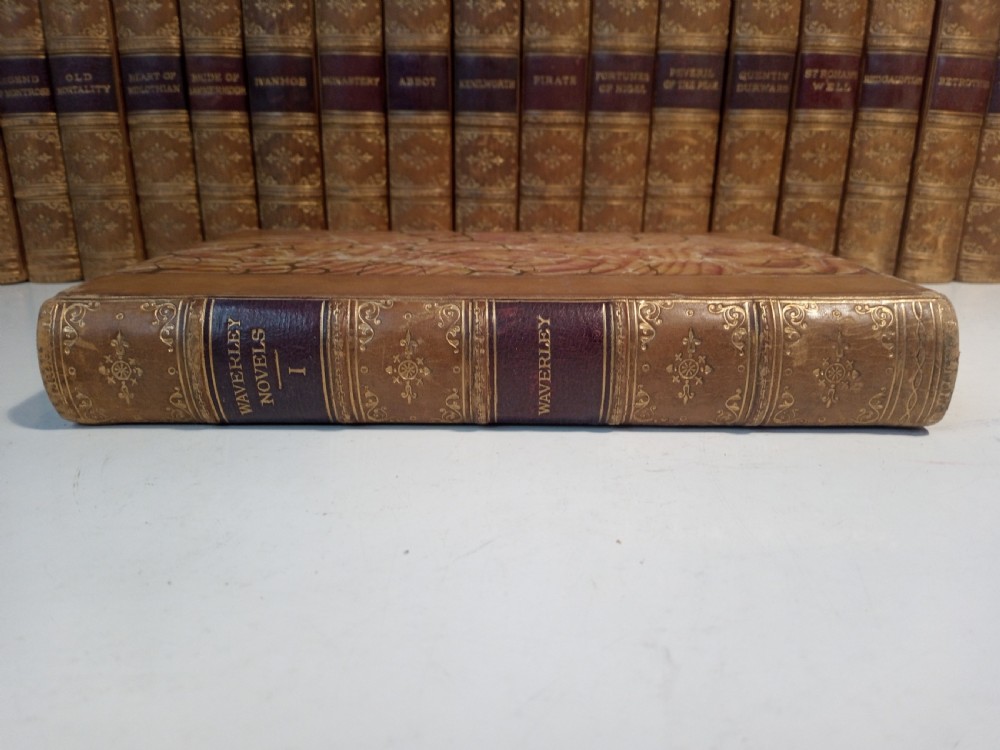 A complete set of 25 Victorian leather-bound Waverley Novels arranged side by side with gilt tooling and red title blocks along the spines. View VI