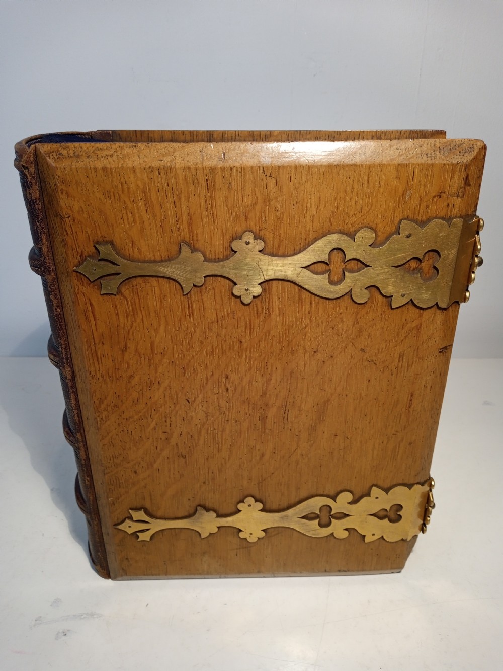 A mid-nineteenth-century Holy Bible featuring a brown leather spine with raised bands and ornate brass mounts over wooden covers. View V
