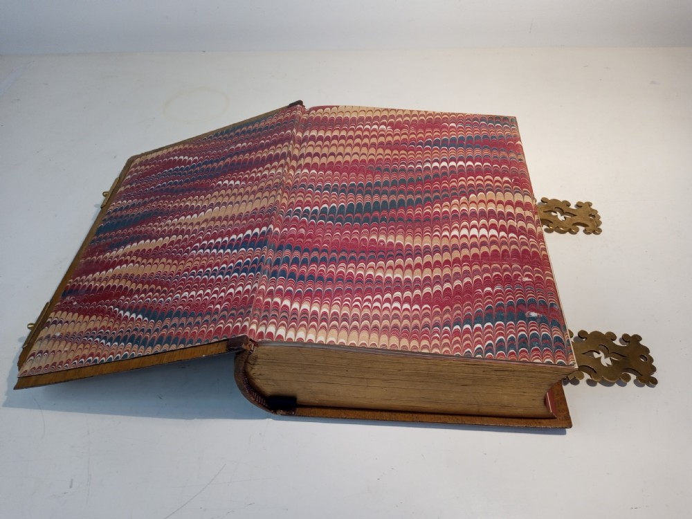 A mid-nineteenth-century Holy Bible featuring a brown leather spine with raised bands and ornate brass mounts over wooden covers. View X