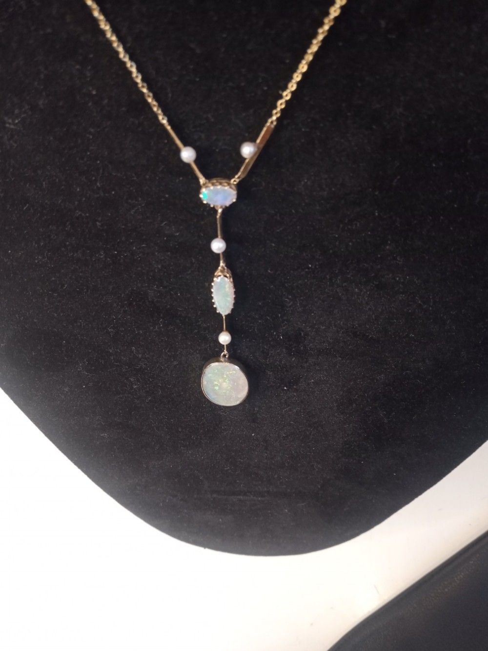 An Art Deco period gold chain necklace featuring a vertical drop pendant set with cabochon opals and small pearls. View III