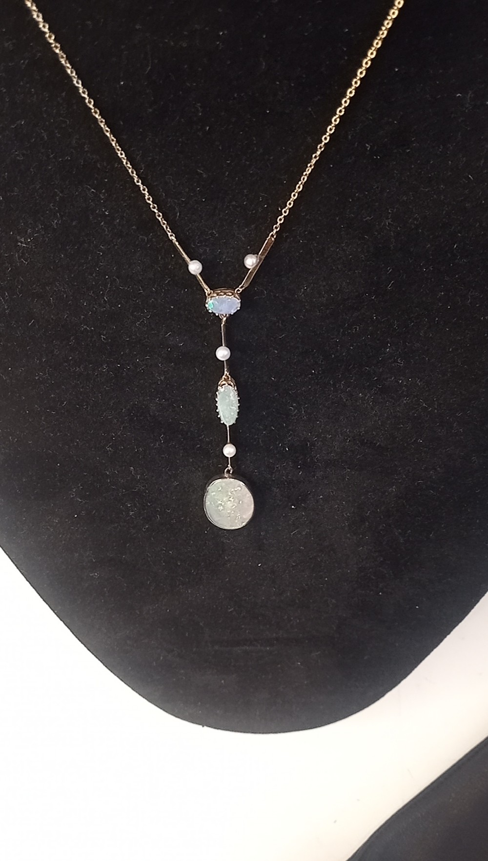 An Art Deco period gold chain necklace featuring a vertical drop pendant set with cabochon opals and small pearls. View IV
